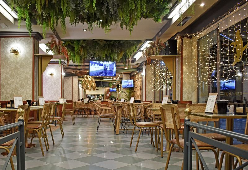 Interior de la cafetería restaurante Anahuac. Zona de mesas con jardín vertical y de techo, una decoración moderna y actual.